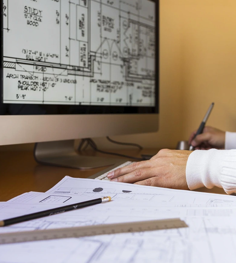 manos de diseñadora técnica con ordenador y pantalla