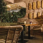 mesa, espejo, pared de ladrillo y plantas en local comercial